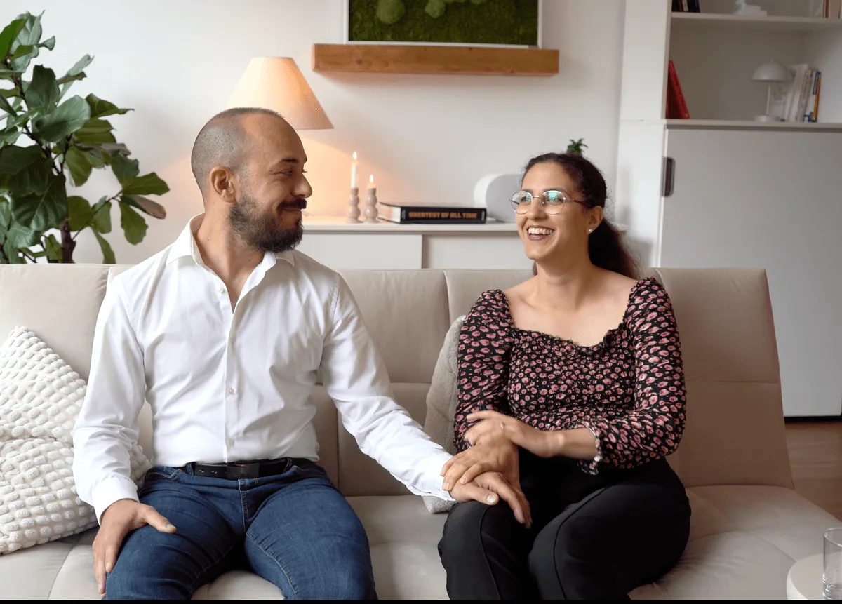 Ein Paar sitzt zusammen auf dem Sofa und hält sich an den Händen
